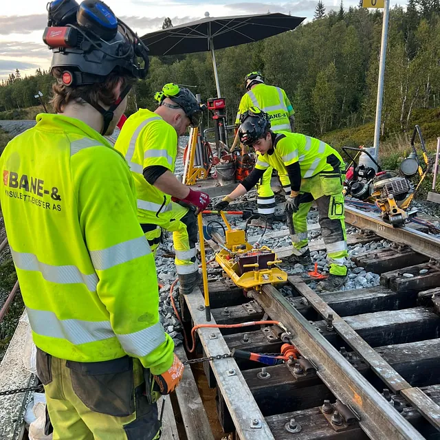 Team justerer jernbaneskinner med spesialverktøy i felt